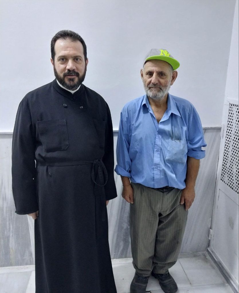 Priester Basilios mit einem älteren Begünstigten des Wohltätigkeitsrestaurants